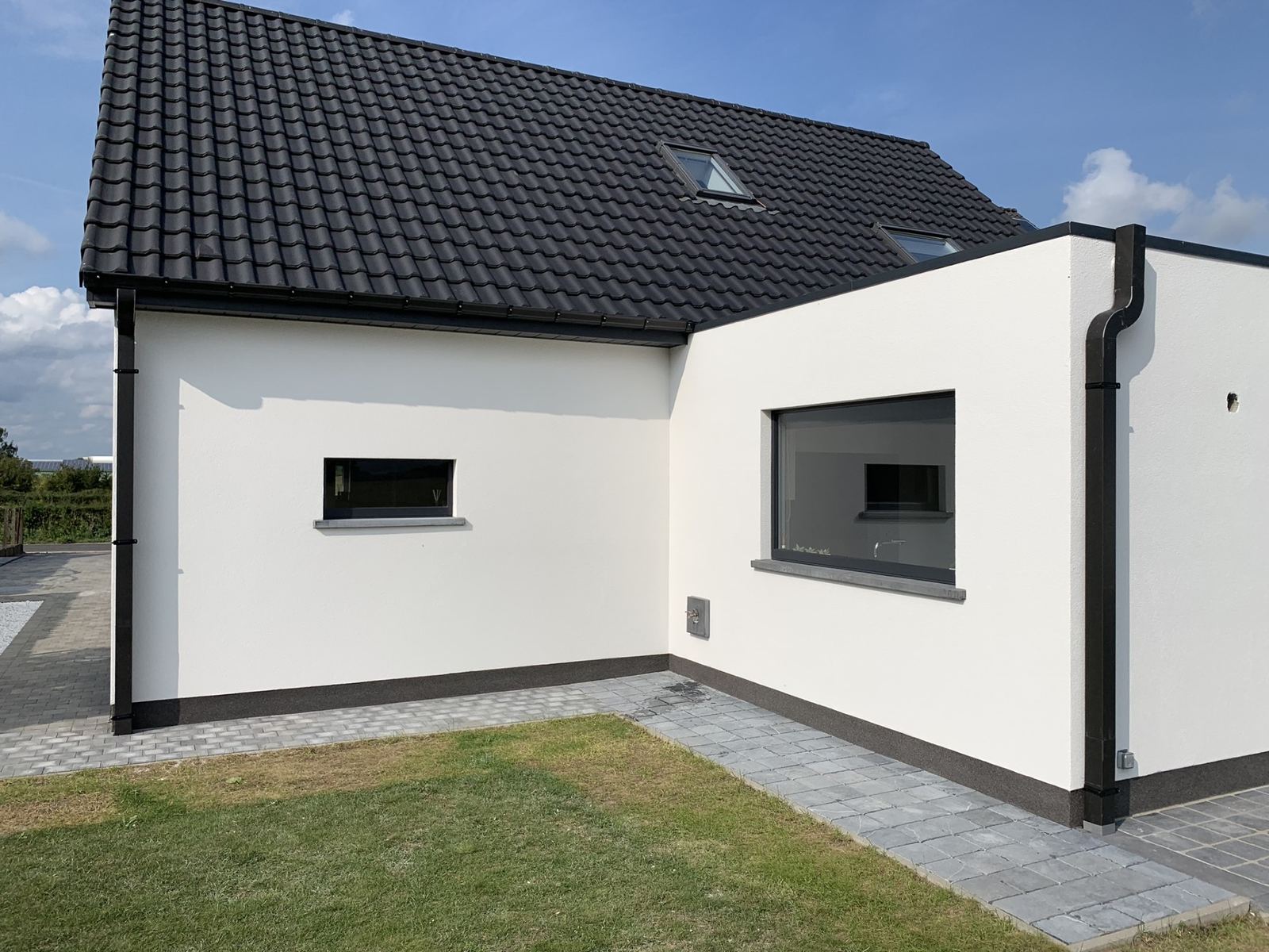 Witte gepleisterde woning met zwarte dakgoot en pannendak